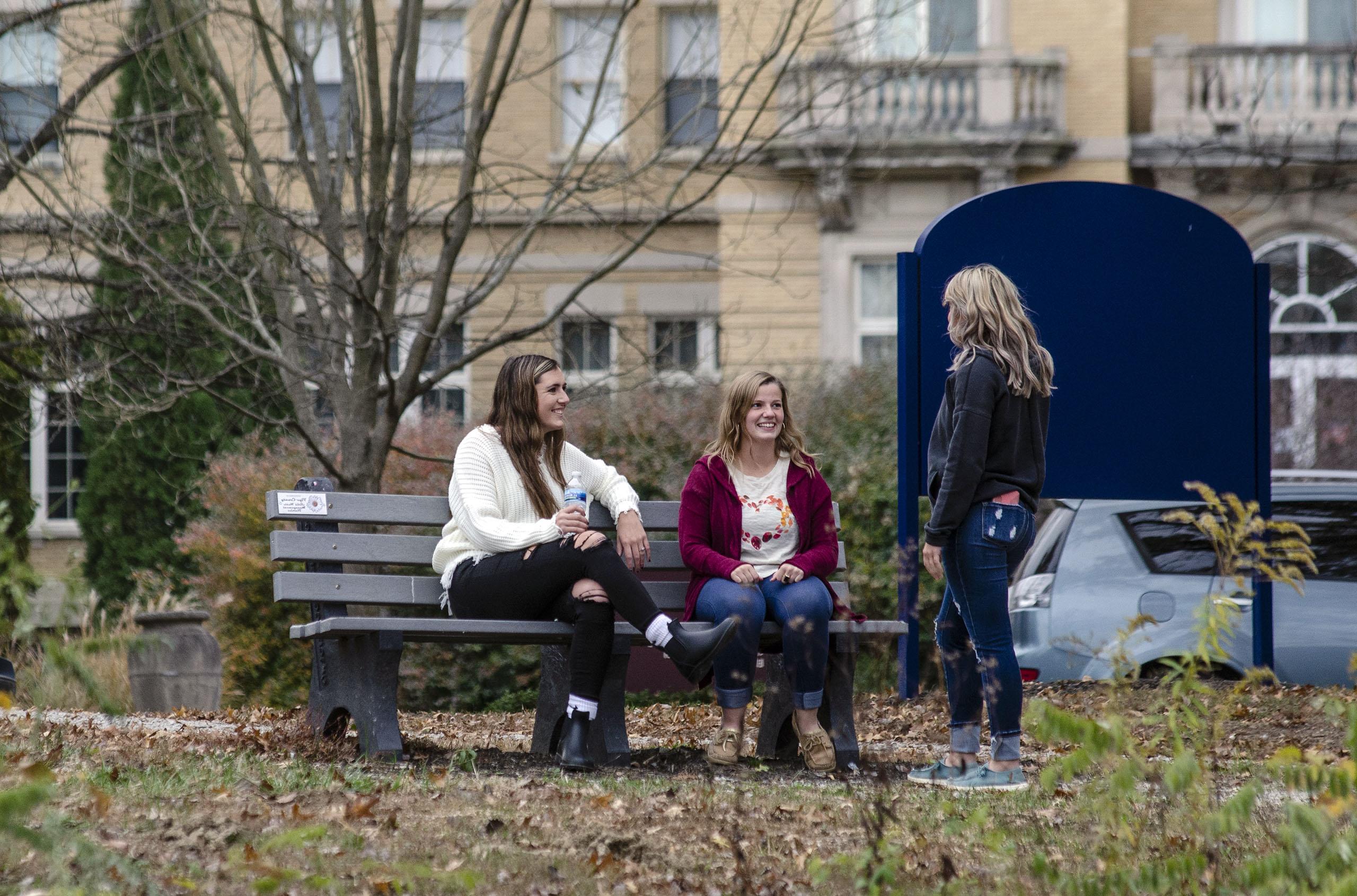 Students on a bench in front of Le Fer Hall